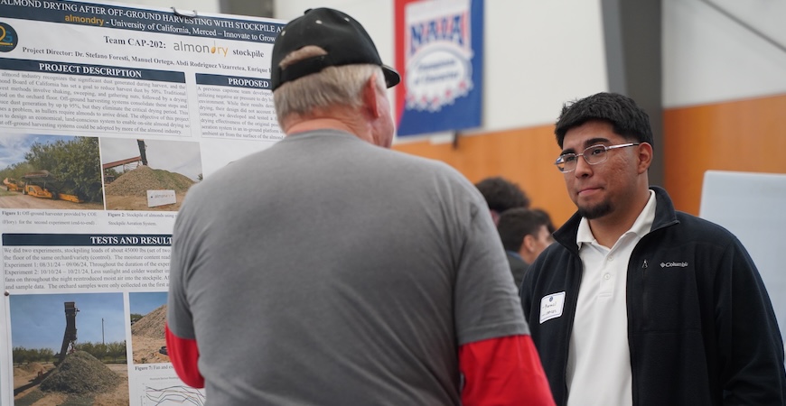 A student is depicted in front of a poster describing the almonry stockpile project at UC Merced.